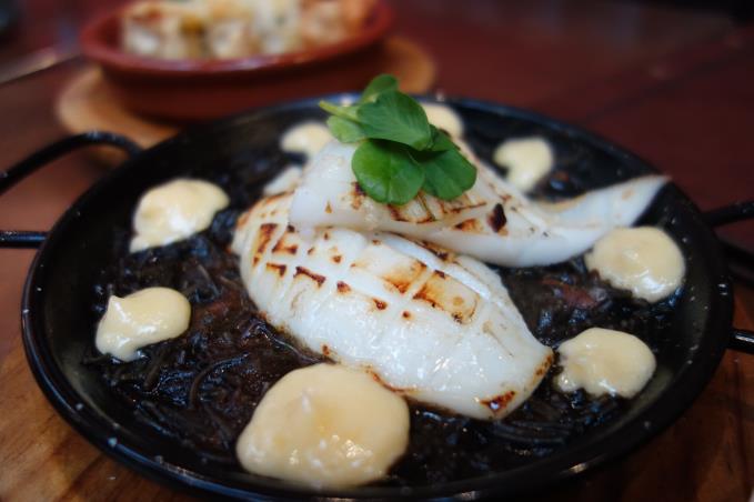 Cuttlefish over a bed of fiduela noodles in a rich squid ink and seafood sauce