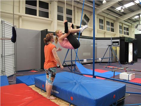 Sian teaching trapeze to a student at The Circus House