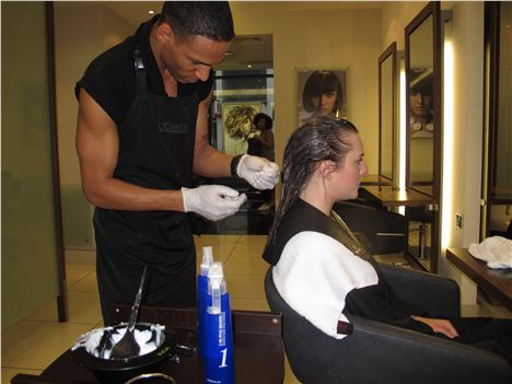 Ben tests the elasticity of Helen's hair after applying the perming solution