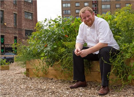 Robert Owen Brown squats down in some Salford bushes