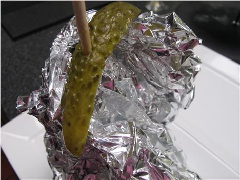 Pleasantly folded burger for take-out with gherkin atop